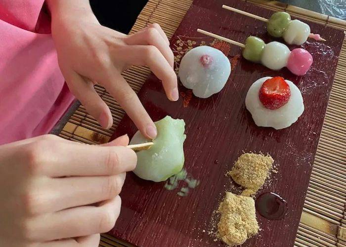 Someone attempting to shape fresh mochi into shapes with wooden tools.